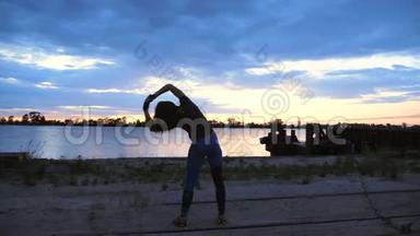 美丽，苗条的年轻女子从事健身，表演力量练习.. 黎明时分，沿着沙漠码头