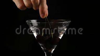 樱桃被扔进一个杯子里，酒精鸡尾酒在黑暗的背景下。 准备鸡尾酒和派对概念。 <strong>慢慢慢慢</strong>
