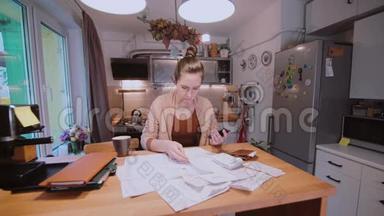 年轻女子坐在厨房的桌子旁计<strong>算账</strong>单。 家庭账户部。 去查账单。