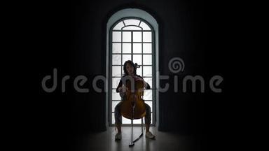 晚上，女孩在大提琴上演奏一首音乐作品，靠在窗户上