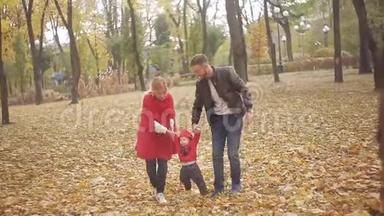 秋天在公园里散步的美丽家庭。 一个<strong>小孩</strong>学会和他的父母一起<strong>走路</strong>