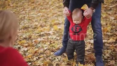 婴儿学会走路。 爸爸妈妈帮助儿子迈出第一步
