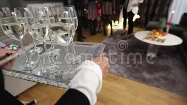 一个女人端着酒杯，酒杯上放着饮料，酒杯上放着香槟或水，放在银盘上