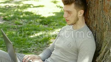 公园里一个树底下的人用笔记本电脑工作