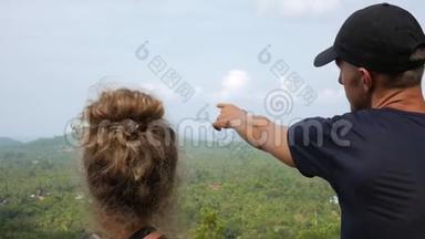 年轻的徒步旅行者夫妇指指点点，谈论美丽的山脉热带森林景观。 戈芬加