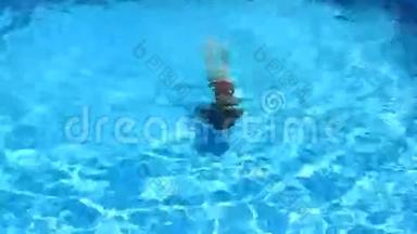 那孩子正在游泳池的蓝色水里游泳。从上面看。女孩在游泳池里潜入水中