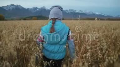 <strong>小女孩</strong>走在麦田里。 孩子<strong>奔跑</strong>的背景是美丽的山脉和白雪覆盖的山峰。 儿童