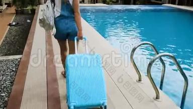 戴着帽子和<strong>工作服</strong>的金发女孩在一家带着蓝色袋子的热带<strong>酒店</strong>安顿下来。