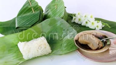 泰国甜点：白色背景下用香蕉叶包裹的粘乎乎的米饭和<strong>蒸蛋</strong>羹。