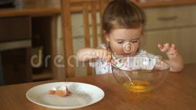 一个可爱的女孩自己用叉子搅动鸡蛋。 炒鸡蛋，蛋糕。 妈妈`帮手。