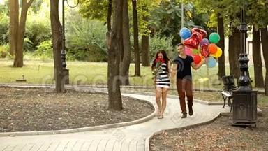 一对爱着气球的年轻夫妇在公园里漫步