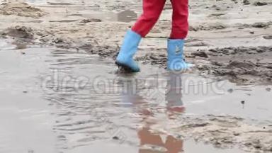 儿童的脚踩在泥坑上，穿蓝色靴子，儿童不安全