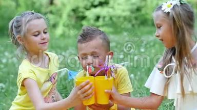 在一片洋甘菊的草地上，靠近一片森林，草地上，有三个孩子在一个黄色的格子上，他们喝着甜饮料