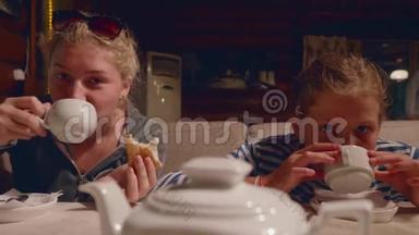 两个年轻的白种人女孩在远足后晚上在咖啡馆喝茶和开玩笑