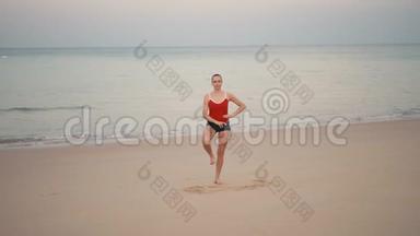 日出前在海滩上穿<strong>红色运动</strong>服的女人练习瑜伽健身<strong>运动</strong>