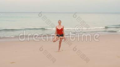 日出前在海滩上穿红色运动服的女人练习瑜伽健身运动