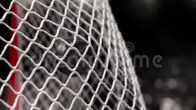 曲棍球冰球在黑色背景上飞入网，照片闪烁。 在慢动作中