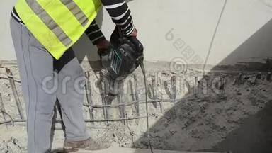 工人正在施工现场用气动锤钻混凝土。 建筑工人在拆除工地使用手提电锤