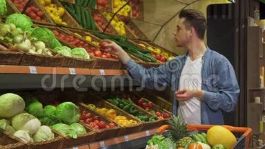 男人从超市的货架上拿着番茄和黄瓜