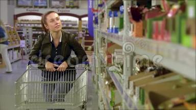 女孩走在批<strong>发货</strong>架上，在商店的手推车里取货，漂亮的年轻妻子在超市购物