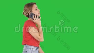 金发女人在绿色屏幕<strong>上走来走去</strong>，在电话里说话，Chroma键。