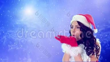 戴着圣诞帽的女孩在蓝色的雪背景上吹着飞舞的雪花。