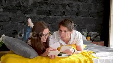 一对夫妇看家庭照片，在家里的床上。