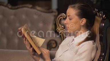 年轻女子在壁炉旁看书。 翻页