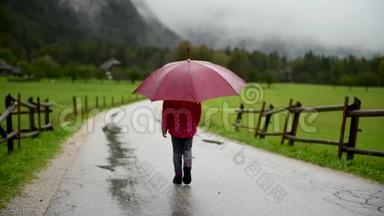 小女孩在乡间小路上雨中散步