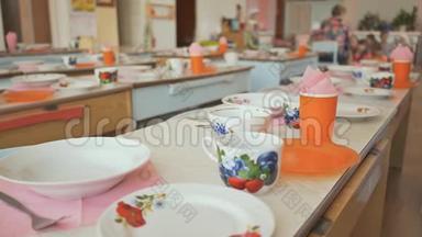 幼儿园的餐桌上有盘子、杯子、叉子和勺子。准备午休。表格设置。