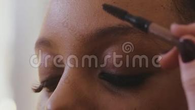 化妆师用刷子梳理眉毛，然后拔毛矫正形状