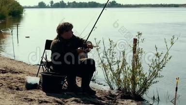 在河边钓鱼的时候，年轻的渔夫在旋转鱼卷
