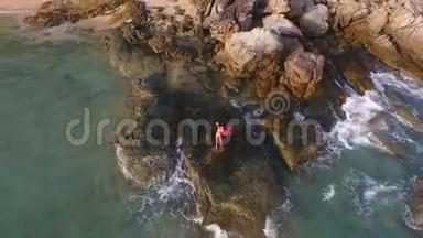 美丽的比基尼年轻女子站在石岸上。 高空飞离高清<strong>慢镜头视频</strong>。 泰国普吉岛。