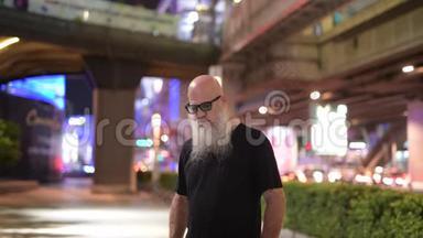 一个成熟的秃头游客在夜间探索城市街道