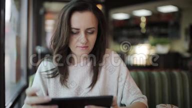 咖啡馆里的一位年轻女子用平板电脑和无线上网购物