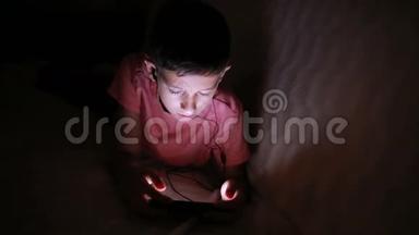 小男孩在床上<strong>玩手机</strong>或智能<strong>手机</strong>。 夜晚