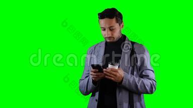 <strong>穿西装的人</strong>用手机拿着咖啡杯。 绿色屏幕，录像。
