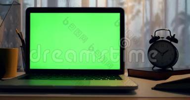 带有绿色屏幕的笔记本电脑。 黑暗的办公室。 多莉向右向左移动。 完美地放置你自己的图像或视频。 技术绿屏