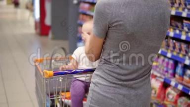 年轻的母亲带着她的小宝宝坐在超市的购物车里，推着购物车向前走，走着