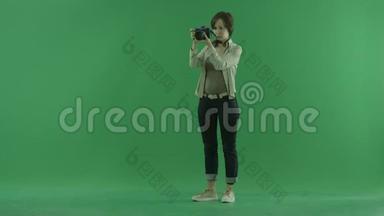一位年轻女子正在绿色屏幕上调整她的相机