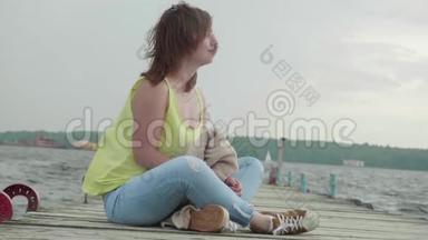 年轻女子坐在古老的<strong>木墩</strong>上，在多云的下午看着前方