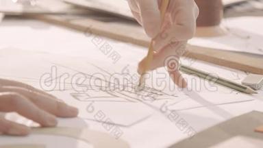 时装设计师在工作室画画。 女人`手在纸上画画。 特写