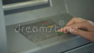 <strong>输入密码</strong>的妇女在自动取款机上取款