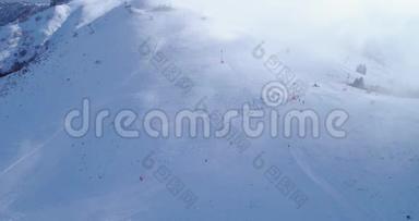 侧面空中飞越冬季雪山山顶滑雪道度假村与滑雪者滑雪。 晴天，雾蒙蒙的云.. 雾升起了