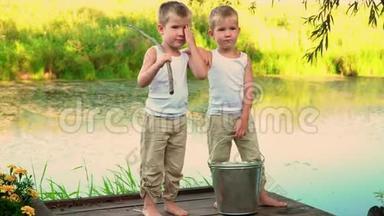 孩子们站在池塘的码头上。 美丽的兄弟在湖边。 夏日。 暑假。