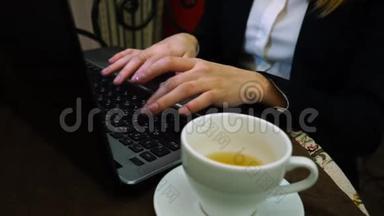 女人用手在<strong>笔记本</strong>电脑键盘上打印文字，<strong>上面</strong>有一杯绿茶