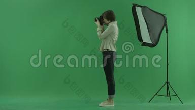 一位年轻女子在绿色屏幕上<strong>左手</strong>边拍照，并纠正站立的模特