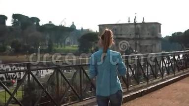 女人走在意大利罗马的街道上，用智能手机拍摄君士坦丁拱门竞技场的照片。 慢动作。