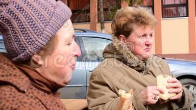 两位年长的妇女赤手空拳地在街上吃猪肉香肠，在塞尔维亚伏伊伏丁那的贝洛布拉<strong>托举</strong>行的宰猪节，