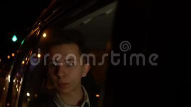 年轻英俊的少年在夜间城市和司机一起乘坐出租车旅行的肖像。 4k个镜头